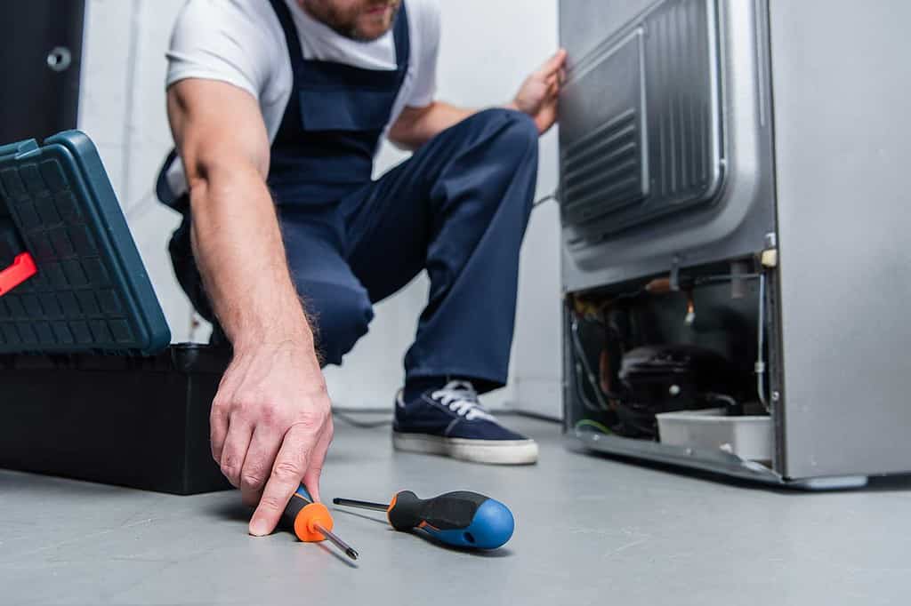 Fridge Repair Mississauga - Man repairing a Refrigerator - Dial an applianceman