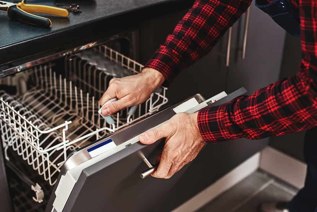 dishwasher repair Edmonton - Repair man repairing a dishwasher